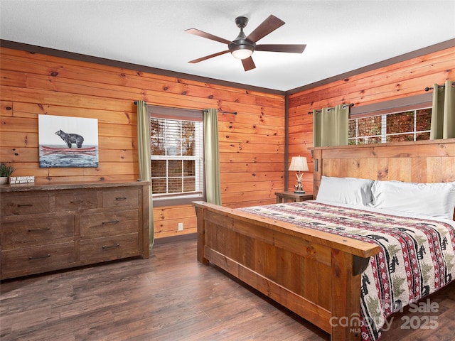 bedroom featuring ceiling fan, wooden walls, and dark hardwood / wood-style floors