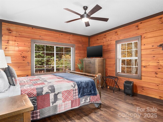 bedroom with ceiling fan, wood-type flooring, and wooden walls