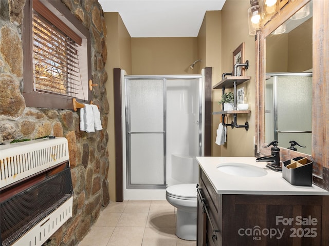 bathroom featuring heating unit, vanity, walk in shower, toilet, and tile patterned floors