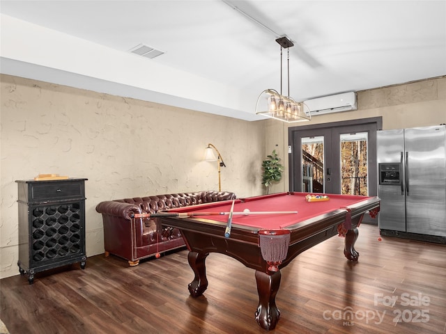 rec room with dark hardwood / wood-style floors, pool table, a wall unit AC, and french doors