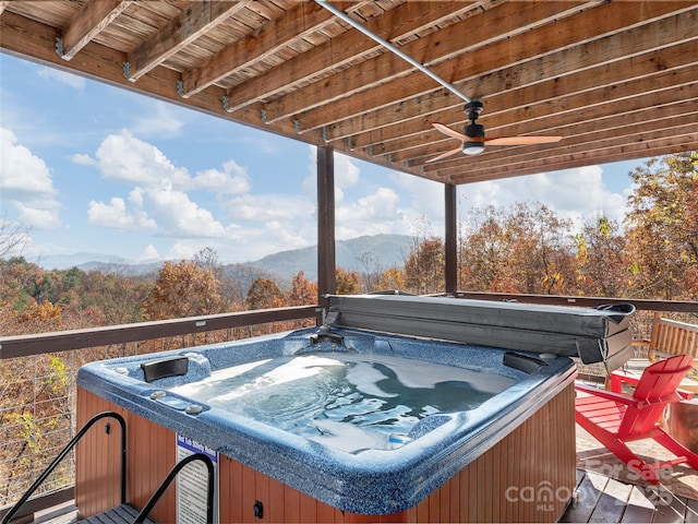 wooden deck with a hot tub, a mountain view, and ceiling fan