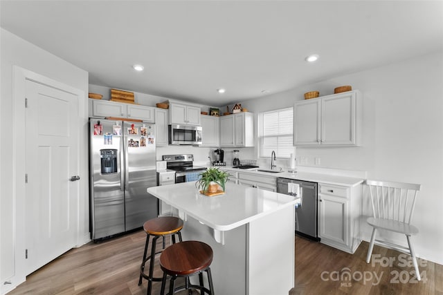 kitchen with a kitchen island, dark wood-type flooring, sink, a breakfast bar, and appliances with stainless steel finishes