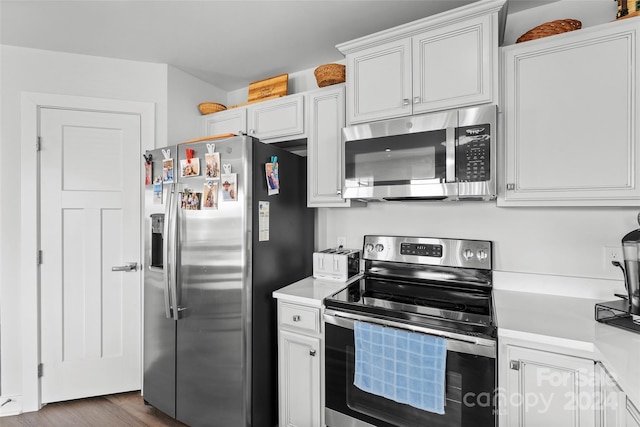 kitchen with white cabinets, stainless steel appliances, and dark hardwood / wood-style floors