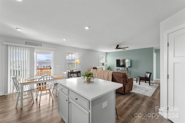 kitchen with a kitchen bar, a kitchen island, dark hardwood / wood-style flooring, ceiling fan, and white cabinets