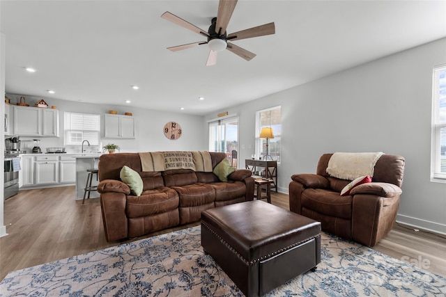 living room with sink, light hardwood / wood-style flooring, and ceiling fan