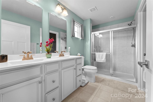 bathroom featuring vanity, toilet, a shower with shower door, and tile patterned flooring