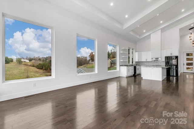 unfurnished living room featuring recessed lighting, a high ceiling, visible vents, baseboards, and dark wood finished floors