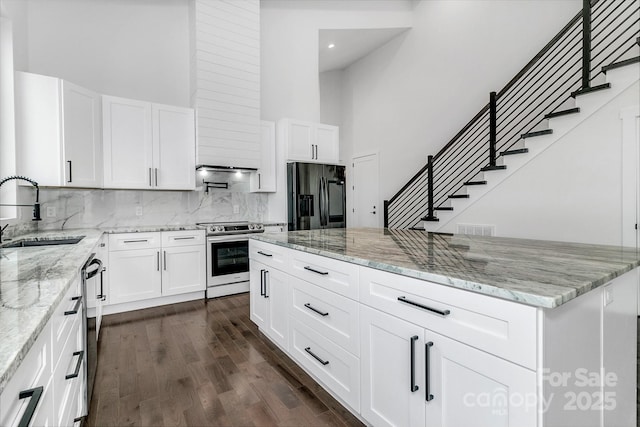 kitchen featuring stainless steel appliances, visible vents, white cabinets, a sink, and light stone countertops