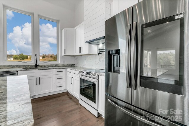 kitchen with stainless steel appliances, light stone counters, a sink, and white cabinetry