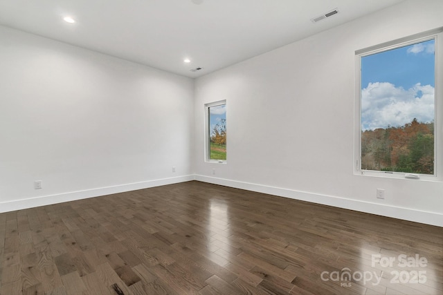 unfurnished room with dark wood finished floors, visible vents, and baseboards