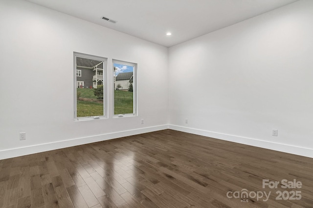 unfurnished room with baseboards, visible vents, dark wood finished floors, and recessed lighting