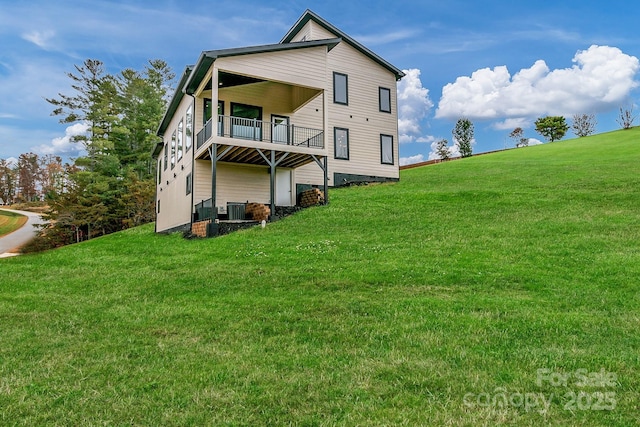 rear view of property with cooling unit, a yard, and a balcony