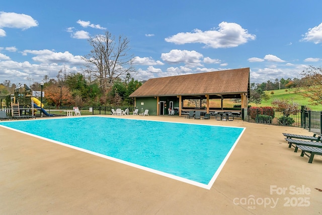 pool featuring playground community, a water slide, a patio, and fence