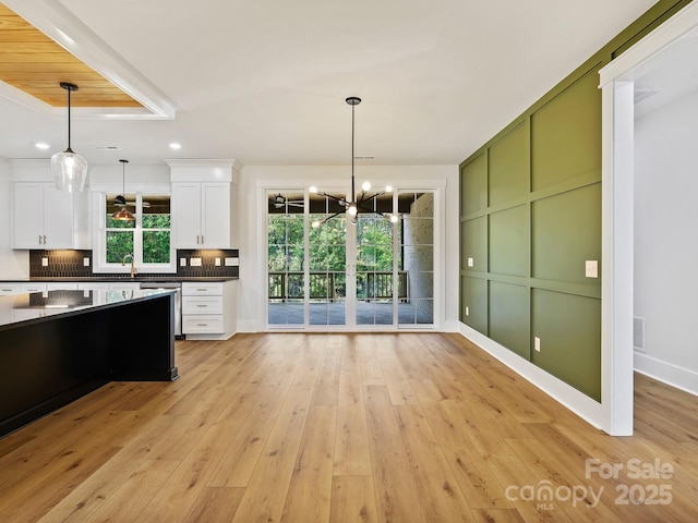 kitchen featuring white cabinets, tasteful backsplash, light hardwood / wood-style floors, and pendant lighting