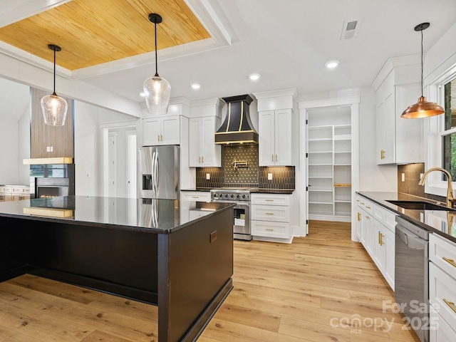 kitchen with sink, white cabinets, stainless steel appliances, and custom range hood