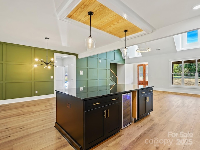 kitchen with light hardwood / wood-style floors, beverage cooler, a kitchen island, and decorative light fixtures