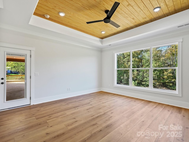 unfurnished room with a tray ceiling, ceiling fan, light wood-type flooring, and wooden ceiling