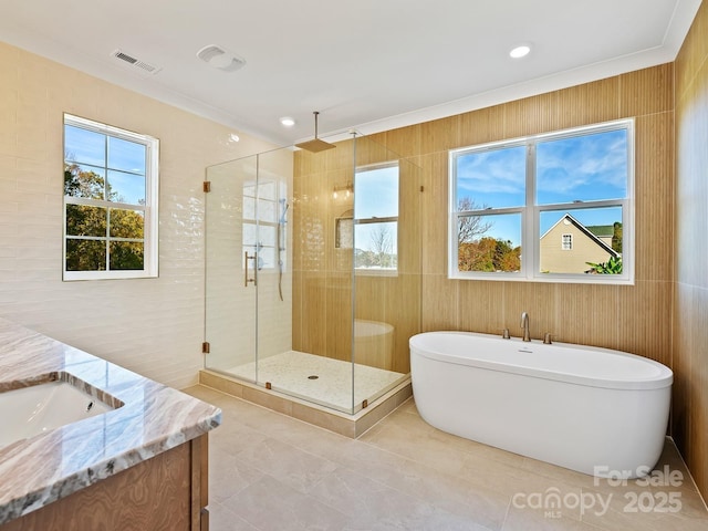 bathroom with plus walk in shower, tile walls, vanity, and ornamental molding