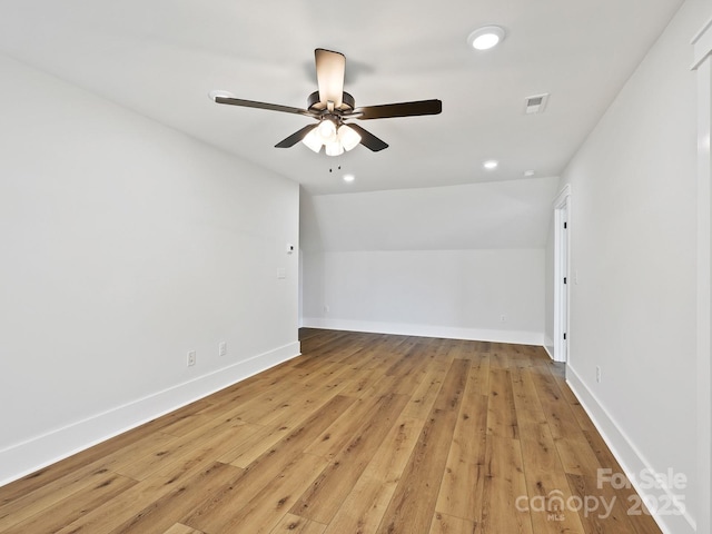 spare room featuring light hardwood / wood-style floors, vaulted ceiling, and ceiling fan