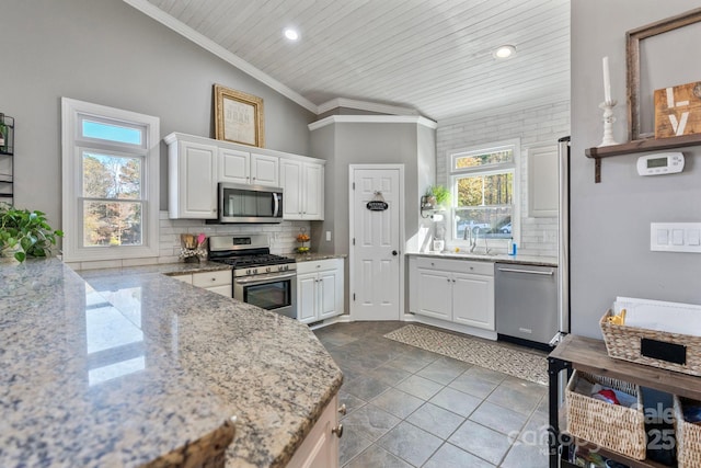 kitchen with lofted ceiling, sink, white cabinetry, and stainless steel appliances