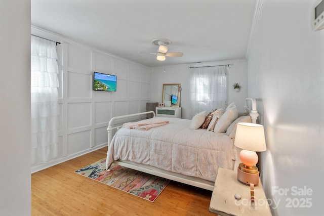 bedroom with hardwood / wood-style floors, ceiling fan, and crown molding