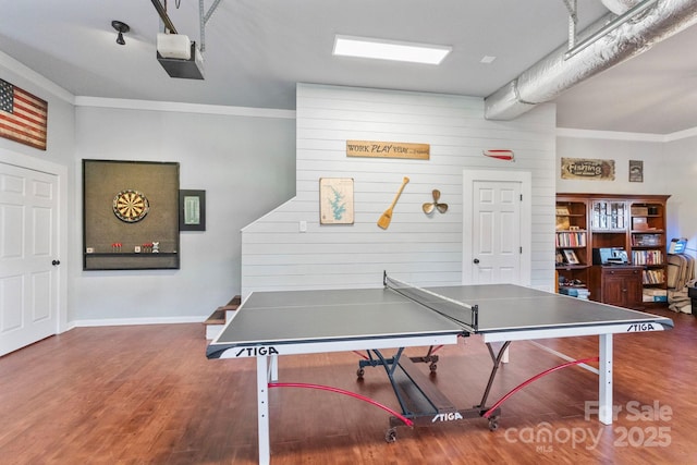 recreation room featuring wooden walls, dark hardwood / wood-style flooring, and ornamental molding