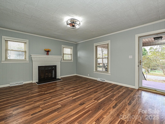 unfurnished living room with a brick fireplace, crown molding, and dark wood-type flooring