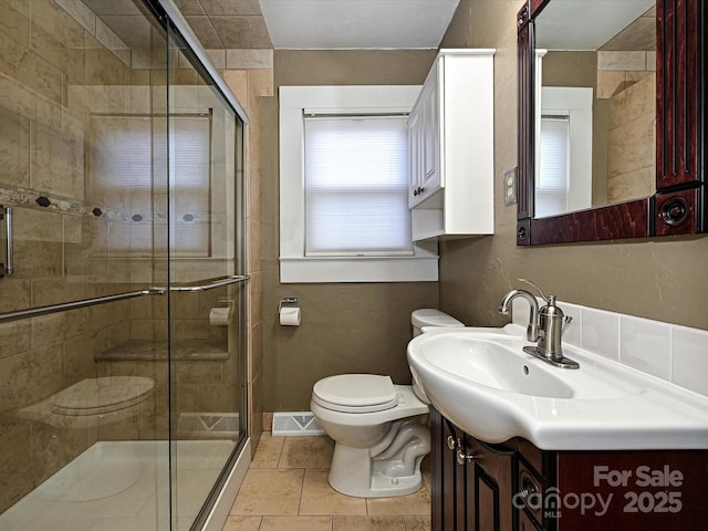 bathroom with toilet, a shower with shower door, tile patterned floors, and vanity