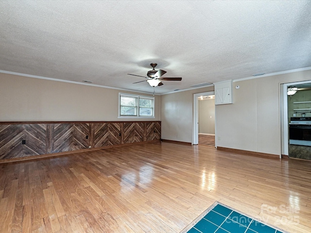 empty room with ceiling fan, crown molding, a textured ceiling, and wood-type flooring