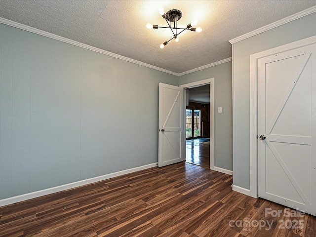 empty room with a textured ceiling, dark hardwood / wood-style flooring, and ornamental molding