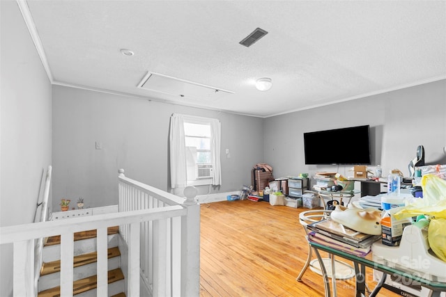 bedroom featuring a crib, a textured ceiling, ornamental molding, and hardwood / wood-style flooring