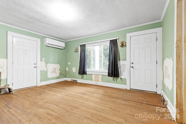 entrance foyer with a textured ceiling, ornamental molding, hardwood / wood-style flooring, and a wall mounted air conditioner