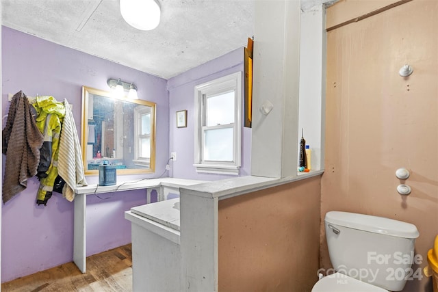 bathroom with hardwood / wood-style flooring, a textured ceiling, and toilet