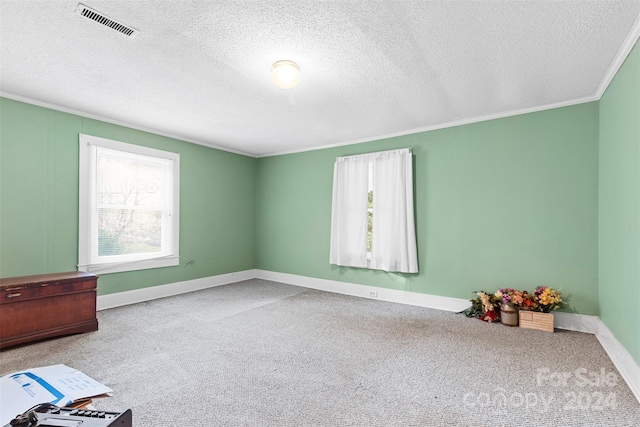 unfurnished room featuring ornamental molding, light colored carpet, and a textured ceiling