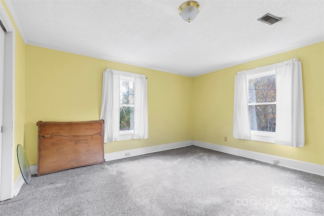 unfurnished room featuring a textured ceiling, ornamental molding, and carpet floors