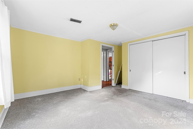 unfurnished bedroom with a closet, carpet floors, and ornamental molding