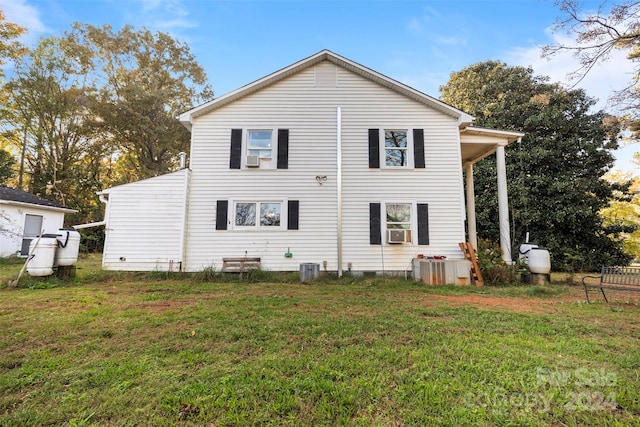 rear view of property featuring a lawn and cooling unit