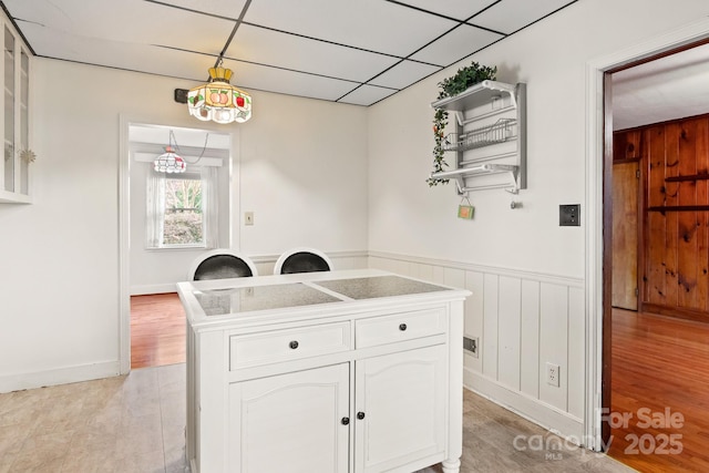 kitchen featuring a drop ceiling, white cabinets, and light wood-type flooring