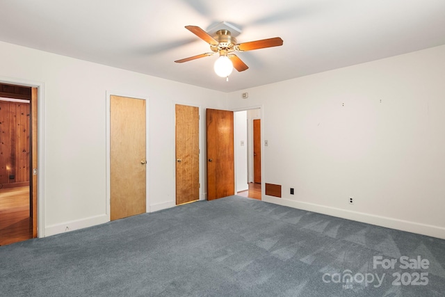 unfurnished bedroom with ceiling fan, carpet, and two closets