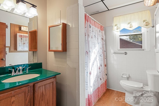 bathroom with hardwood / wood-style floors, vanity, toilet, and tile walls