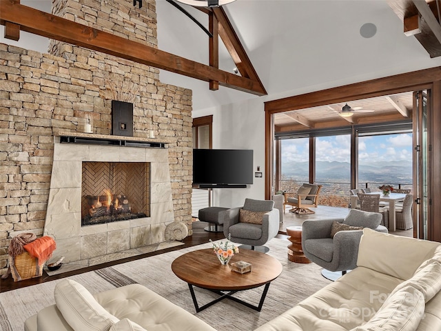 living room with beamed ceiling, a fireplace, high vaulted ceiling, and light hardwood / wood-style flooring