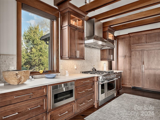 kitchen with wall chimney exhaust hood, high end appliances, dark wood-type flooring, and a wealth of natural light