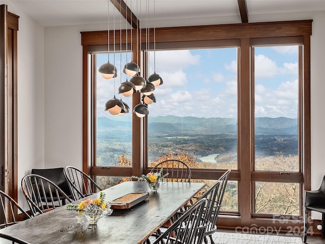 dining room with a mountain view, beamed ceiling, an inviting chandelier, and a healthy amount of sunlight