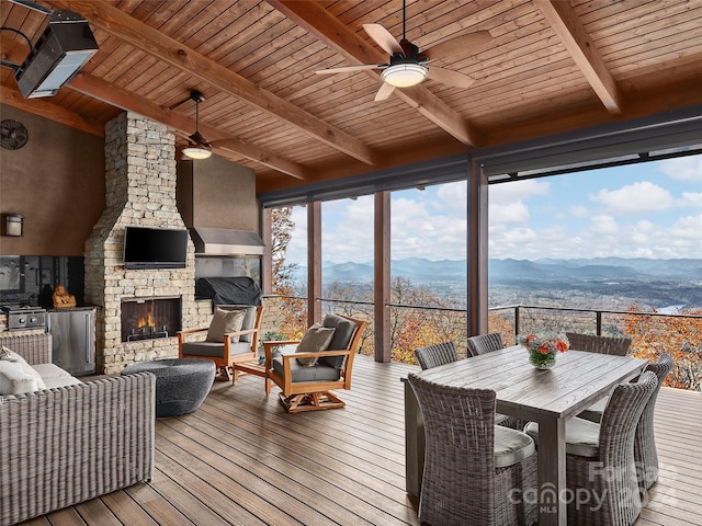 sunroom / solarium featuring vaulted ceiling with beams, ceiling fan, wood ceiling, and an outdoor stone fireplace