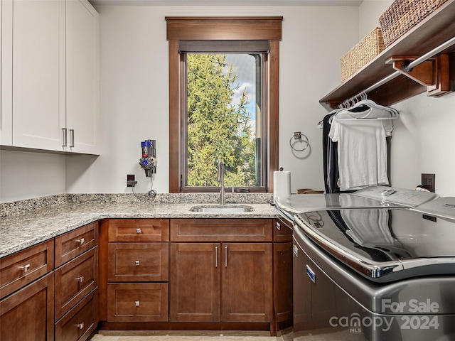 laundry room featuring cabinets, independent washer and dryer, and sink