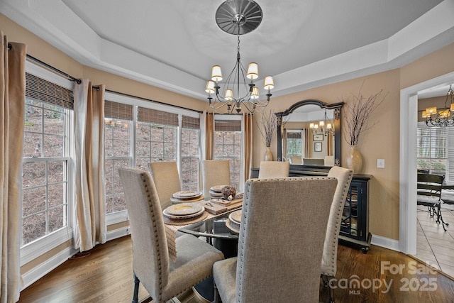 dining area with a notable chandelier, dark hardwood / wood-style floors, beverage cooler, and a tray ceiling