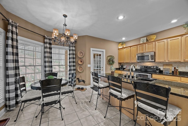 kitchen with light brown cabinets, pendant lighting, appliances with stainless steel finishes, backsplash, and light tile patterned flooring