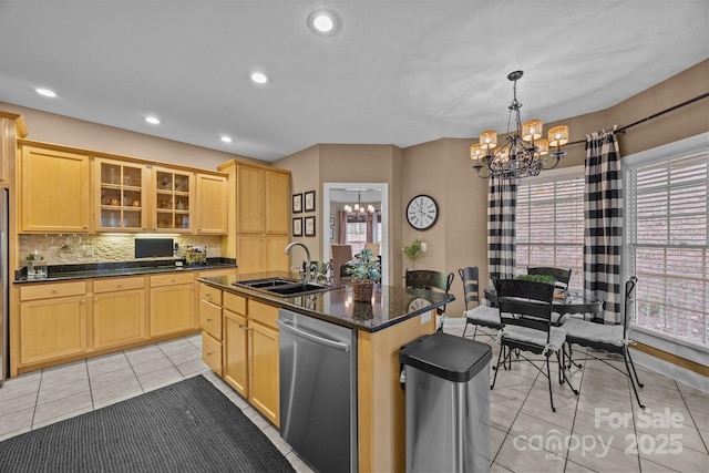 kitchen featuring a notable chandelier, dishwasher, light tile patterned floors, sink, and an island with sink