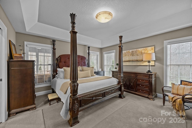 carpeted bedroom featuring a textured ceiling and a tray ceiling