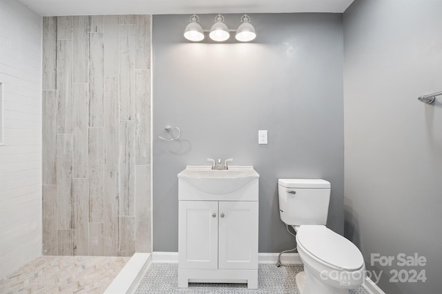 bathroom featuring vanity, a tile shower, and toilet